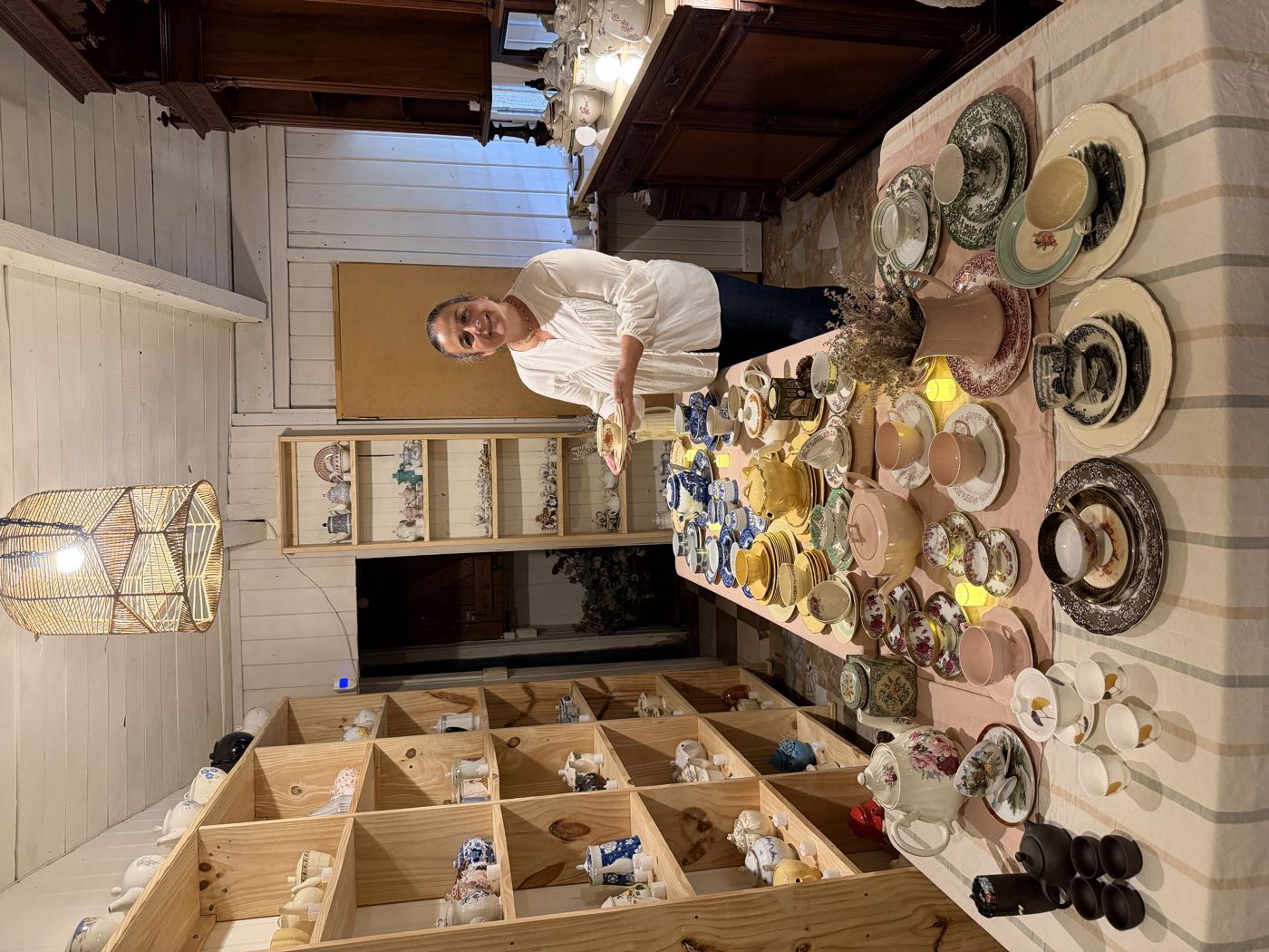 Sala de la colección con estantes de teteras y tazas y una mesa servida