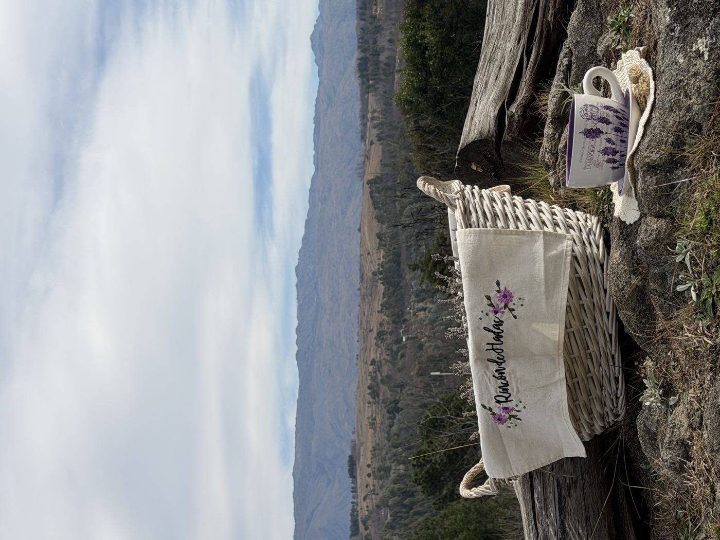 Canasta con el bordado de Rincón de Hadas y una taza con lavandas frente a las sierras